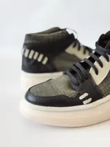 Zapatillas deportivas de caña alta con estampado de piel de reptil en tonos verde y negro, detalles en blanco y suela gruesa blanca.