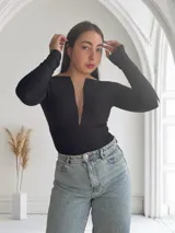 Body negro de mangas largas con escote en V y detalle de tul transparente en el centro.