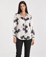 Camisa de manga larga color beige con estampado de grullas negras, cuello clásico y cierre frontal de botones.