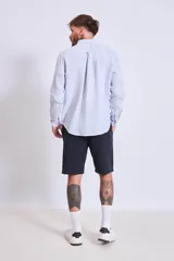Camisa de corte regular con diseño de rayas verticales finas en tonos claros, cuello clásico y mangas largas con puños abotonados.