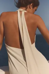 Vestido largo color blanco con cuello halter y escote en pico pronunciado. Detalle de frunces, forro interior y abertura en la espalda.