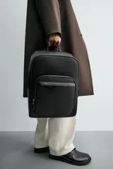 Mochila de diseño minimalista con acabado grabado, compartimento principal con cierre, espacio interior para dispositivos electrónicos de hasta 13 pulgadas, bolsillos frontales con cierre, parte posterior acolchada con banda de sujeción para equipaje, asa de mano y correas de hombro ajustables y acolchadas.