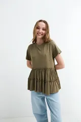 Remera de algodón color verde militar con cuello redondo, mangas cortas y detalle de volados fruncidos en la parte inferior.