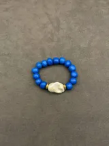 Pulsera elástica compuesta por cuentas de piedra natural en color azul, con una perla de río central flanqueada por dos separadores metálicos dorados.