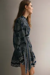 Vestido corto de estilo túnica en color azul marino con estampado paisley, cuello mao, mangas largas con puños anchos abotonados y un cinturón lazada ajustable a la cintura.