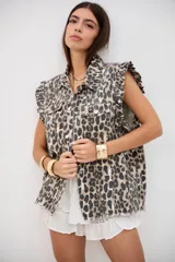 Chaleco de denim con estampado animal print, cuello camisero, cierre frontal con botones metálicos y volados en las sisas.