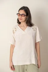 Blusa italiana color crudo de lino con escote en V y mangas cortas. Presenta detalle de bordado calado en el canesú.
