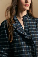 Camisa de algodón a cuadros con diseño de volados frontales, cuello alto y mangas largas con leve volumen.