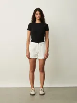Short de jean color blanco roto (off white) de tiro alto, con roturas y terminación deshilachada en el ruedo.