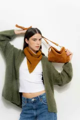 Bandolera pequeña de gamuza color tostado, con correa larga ajustable y cierre superior. Presenta un diseño minimalista y compacto.