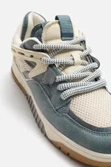 Zapatilla deportiva de caña baja, con cordones, fabricada en combinación de piezas de cuero sintético y malla. Detalle de cordones gruesos. Plantilla OrthoLite®. Suela con detalles a contraste en marrón, gris y blanco.