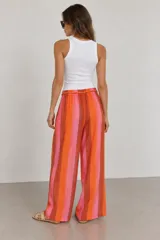 Pantalón de tiro alto y pierna ancha con estampado de rayas verticales en tonos rosados, naranjas y marrones. Cuenta con cintura elástica con cordón de ajuste y bolsillos laterales.