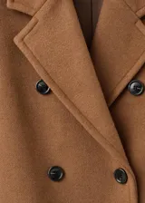 Abrigo largo de paño en color marrón, con diseño recto, cuello con solapas de muesca y cierre frontal de doble botonadura. Presenta mangas largas con puños abotonados y dos bolsillos laterales con solapa.
