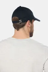 Gorro con visera de lona color verde oliva con parche circular de goma negro en el frente.