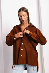 Camisa marrón de gamuza con botones blancos, cuello clásico y corte holgado.