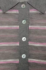 Polo de punto fino confeccionado en lana, con diseño de rayas horizontales en tonos gris, blanco y rosado. Presenta cuello polo, manga larga y cierre frontal con botones.