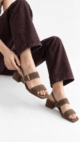 Sandalia de cuero color beige con taco cuadrado de 4 cm, tiras delanteras, tira ajustable con hebilla metálica dorada y tira elástica trasera.
