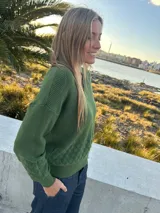 Sweater de punto verde oscuro, confeccionado en hilado de viscosa y lycra, con escote en V y diseño de rombos texturizados en la parte inferior y las mangas.
