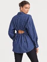 Camisa de denim azul con diseño oversize, cuello camisero, manga larga y cierre frontal de botones.