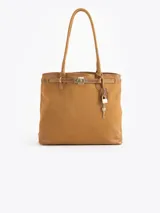 Cartera tipo tote color tostado, confeccionada en cuero vacuno, con asas largas para el hombro, detalles metálicos plateados y un llavero con candado y llave colgante.