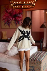 Sweater de tejido de punto en lana merino color crudo, con diseño artístico abstracto en color negro aplicado mediante técnica de fieltro agujado. Presenta cuello redondo, mangas largas y corte holgado.