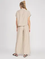 Blusa crop cruzada Allie Rose de tela liviana negra con estampado de lunares blancos, escote en V y cuello camisero.
