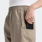 Pantalón cargo color beige, con cintura elástica ajustable con cordón, bolsillos laterales de doble entrada, dobladillo ajustable con broches y etiqueta tejida con el logo de New Balance.