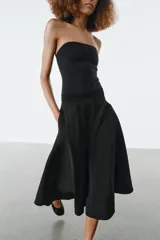 Falda midi de tiro alto en color negro, con diseño en línea evasé y cierre de cremallera oculta en la costura.