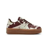 Championes de plataforma con diseño de estampado animal print tipo vaca en tonos marrón y blanco, con cordones marrones y suela de goma color caramelo.