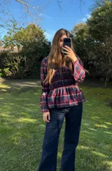 Blusa de manga larga con diseño a cuadros escoceses en tonos bordó, verde y azul. Presenta cuerpo con frunces elastizados y mangas amplias con puños acampanados.