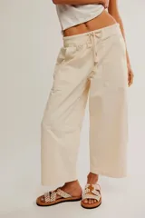 Pantalón de denim blanco de tiro medio con cintura elástica ajustable mediante cordón, bolsillos plaqué delanteros y diseño de corte amplio y holgado.