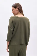 Remera de manga tres cuartos, color verde oliva, con cuello bote y textura arrugada. Corte holgado.