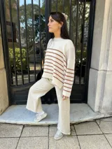 Sweater tejido color crema con rayas horizontales marrones, cuello redondo y corte holgado.