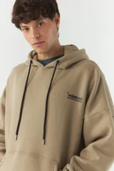 Canguro de felpa color beige con capucha, cordones negros, bolsillo tipo canguro y puños y cintura acanalados. Estampado con el logo de la marca en el pecho y parche con el logo en la manga izquierda.