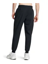 Joggers Under Armour modelo Unstoppable de color negro, confeccionados en tejido técnico elástico con tecnología UA Storm que repele el agua. Presentan corte ajustado en las piernas, cintura elástica con cordón, bolsillos laterales y un bolsillo con cierre sellado en el muslo.