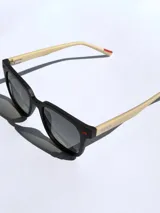 Lentes de sol negros con marco cuadrado y detalles rojos. Lentes con protección UV 400 y tecnología polarizada. Marca Osten, modelo Bali 2602.