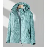 Campera cortaviento impermeable de la marca Uniteduy, color negro con estampado sutil de hojas. Cuenta con capucha, cierre frontal, tres bolsillos externos y uno interno. Es una prenda ultra liviana y transpirable, ideal para actividades al aire libre.