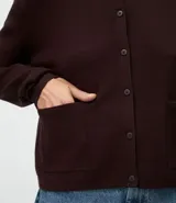 Cardigan de punto color marrón chocolate, con cuello redondo, cierre frontal con botones y mangas largas. Presenta un diseño clásico con acabado canelado en el escote y los puños.