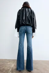 Pantalón jean acampanado de tiro bajo en denim levemente elástico, con bolsillos delanteros decorativos, bolsillo monedero y bolsillos abiertos atrás.