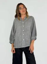 Camisa de corte oversize en color gris, confeccionada en tejido de lino y algodón. Presenta cuello mao, cierre frontal con botones y mangas tres cuartos con terminación abullonada.