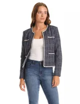 Chaqueta de tejido tweed en tono azul con sutiles destellos de lúrex. Presenta cuello a la base, abertura frontal y bolsillos decorativos. Las mangas largas incluyen detalle de botones metálicos dorados en los puños, y cuenta con vivos a contratono en los bordes.