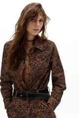 Camisa de pana con estampado floral estilo tapiz en tonos marrones y negros. Presenta cuello clásico, botones frontales forrados y mangas largas con puños.