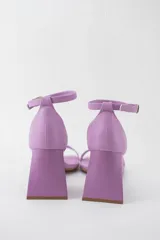 Sandalias color crema con tira delgada sobre los dedos, pulsera al tobillo con hebilla y taco geométrico.