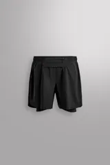 Short de running 2 en 1 color beige, confeccionado en tejido técnico ligero y elástico con malla interior integrada. Presenta cintura elástica ajustable con cordón, bolsillo trasero con cierre y aberturas laterales en el bajo.