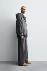 Pantalón jogger de corte wide fit confeccionado en tejido de algodón con interior de rizo. Presenta cintura elástica ajustable con cordón, bandas laterales decorativas, bolsillos laterales y un bolsillo trasero de plastrón. El acabado presenta un efecto lavado que le otorga una apariencia única.