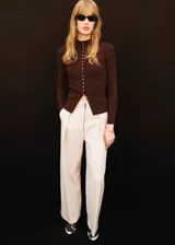 Pantalon de vestir color crema, de corte recto y tiro alto, con cierre frontal de cremallera visible y pliegues laterales.