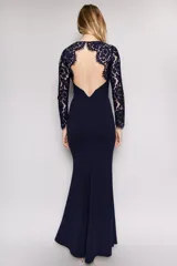 Vestido largo de fiesta color azul marino, con mangas largas de encaje y escote redondo. Presenta un diseño entallado que se ensancha suavemente hacia el ruedo.