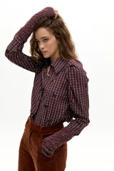 Camisa de manga larga con estampado de cuadros y bordados florales pequeños. Presenta cuello camisero clásico, cierre frontal con botones de nácar y hombros abullonados con frunces.