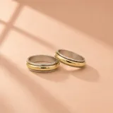 Par de alianzas de diseño bicolor, combinando plata y oro con una franja central dorada y bordes plateados.