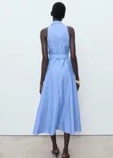Vestido midi celeste a rayas verticales, sin mangas, con cuello camisero, cierre frontal con botones y cinturón forrado con hebilla.